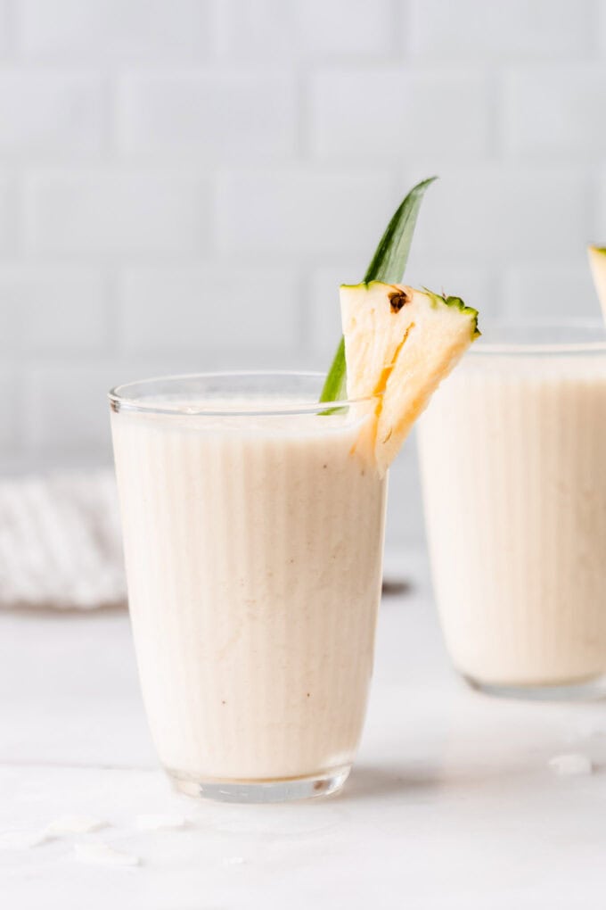 two glasses of pina colada smoothie on a marble contertop