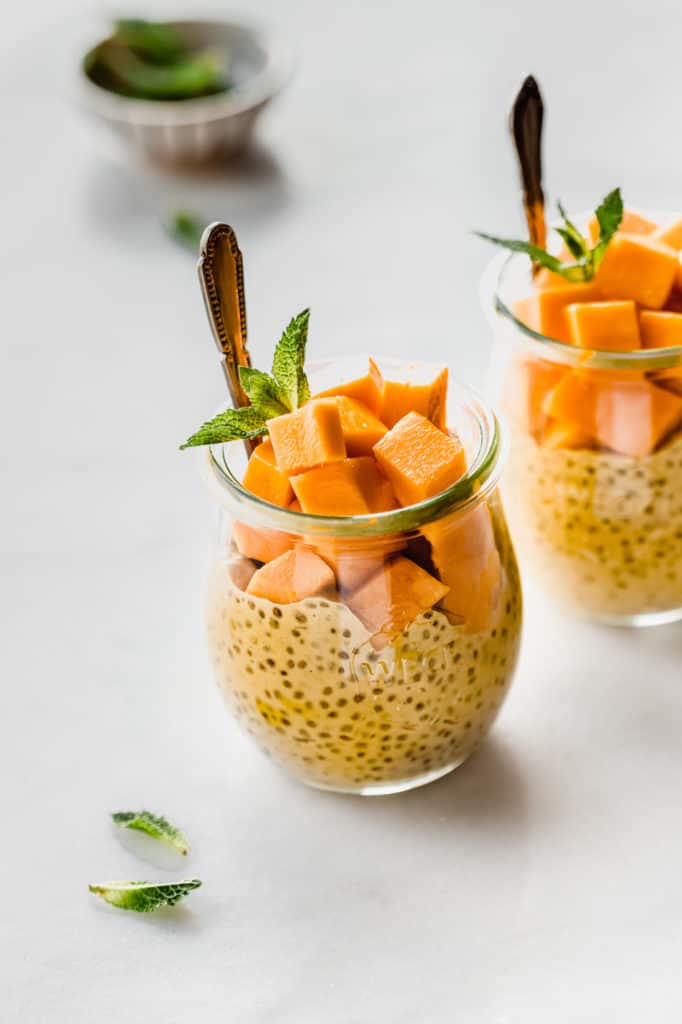 a jar filled with mango chia pudding, cubed mangos and fresh mint