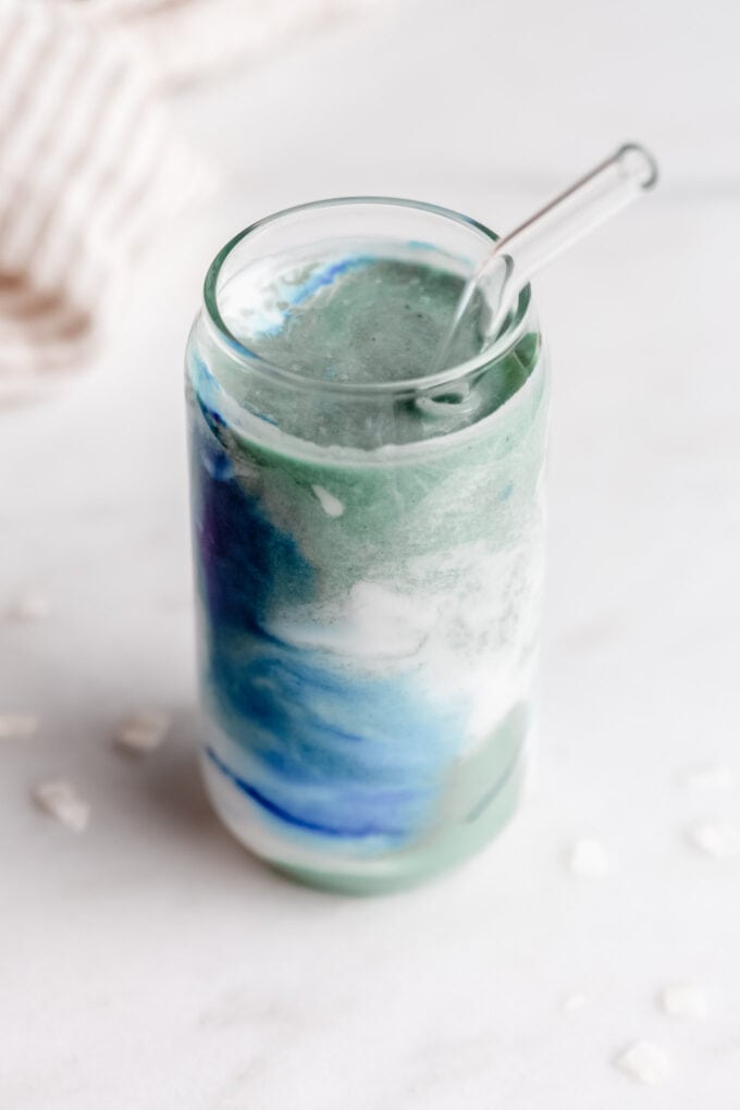 blue spirulina smoothie in a glass with a straw